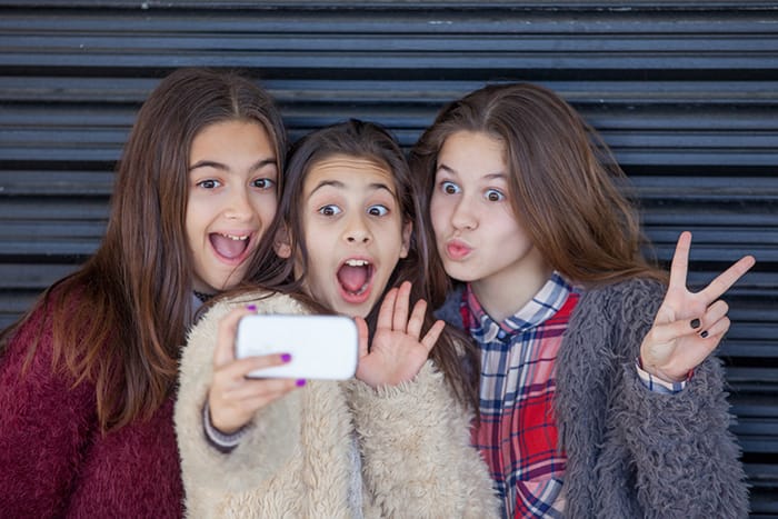 Photo of 3 young people taking a selfie with a metal background.