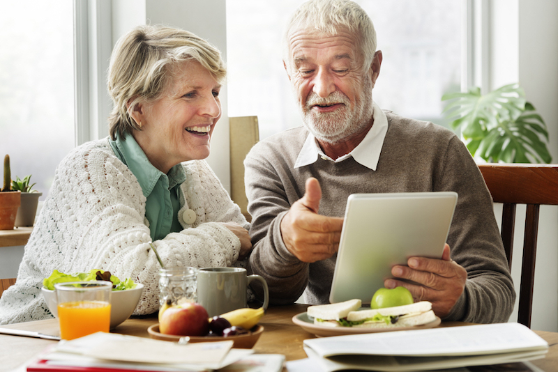 A photo of two seniors looking at a tablet