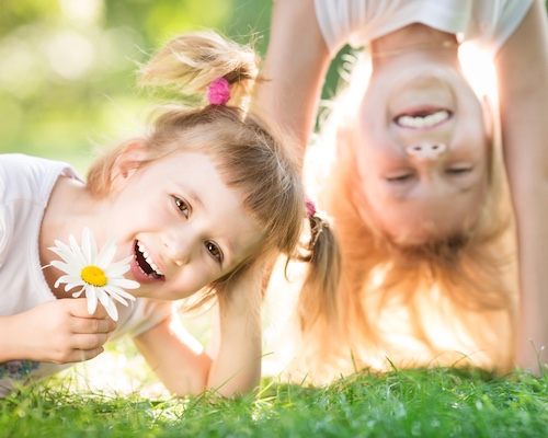 Two kids playing on the grass outside.