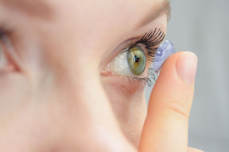 Woman with green eyes putting in a contact lens